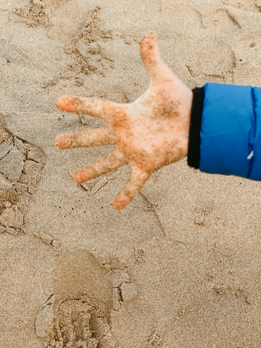 a person's hand holding a frisbee in the sand