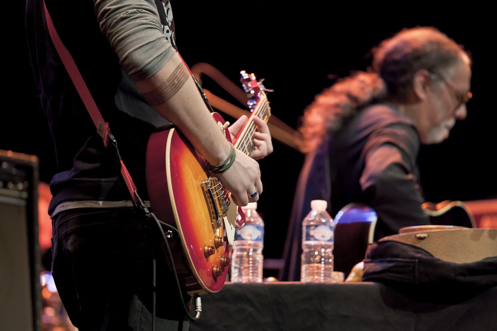 man in black and white striped shirt playing guitar