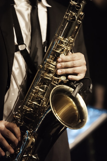 person in white dress shirt holding saxophone