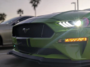 Close-up of a Lamborghini's aggressive front grille with blurred Miami skyline behind.