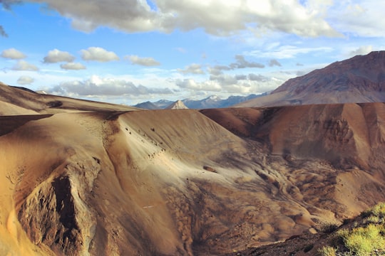 brown rocky mountain under white clouds during daytime in Ladakh India