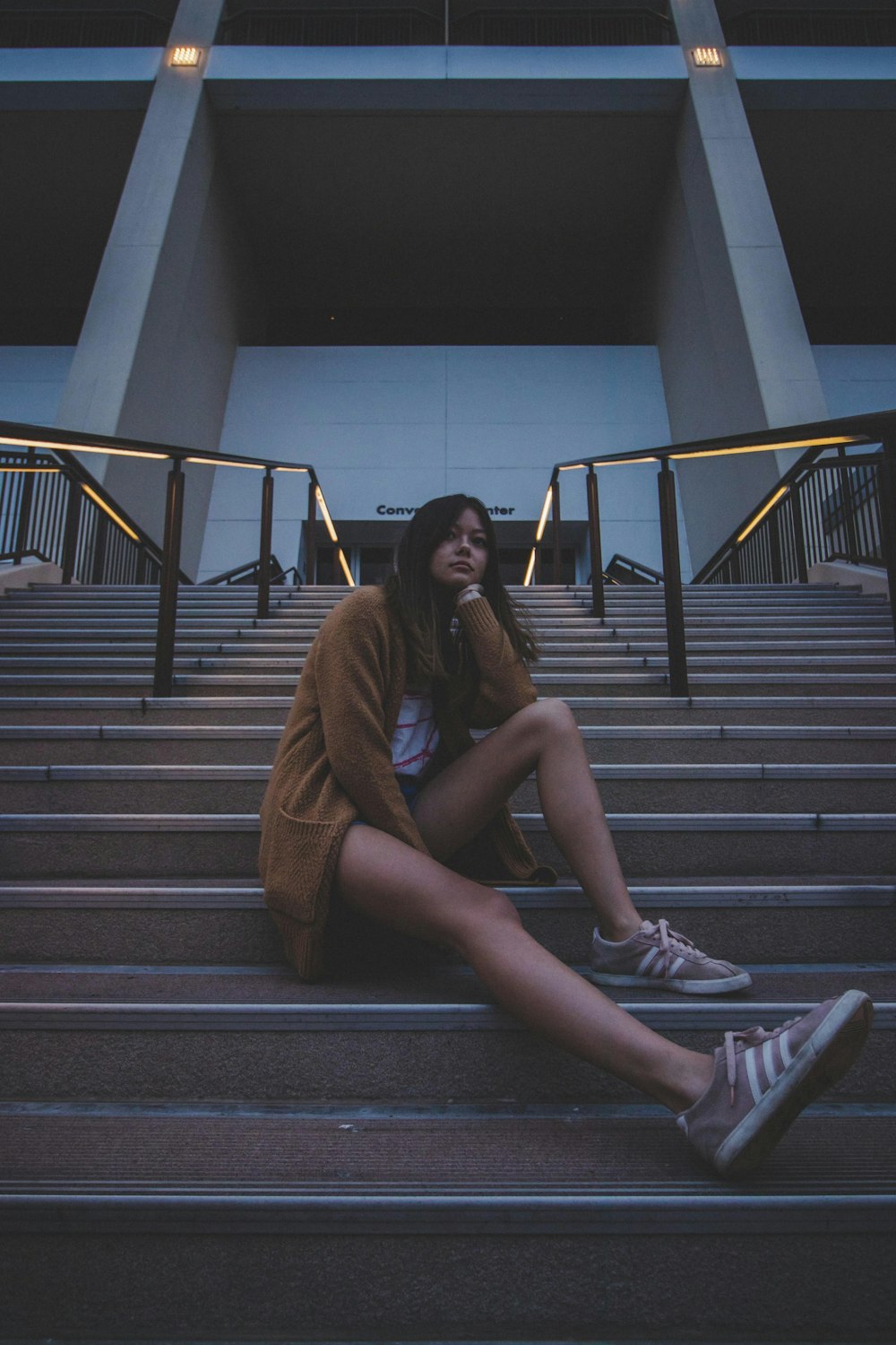 woman in brown coat sitting on stairs