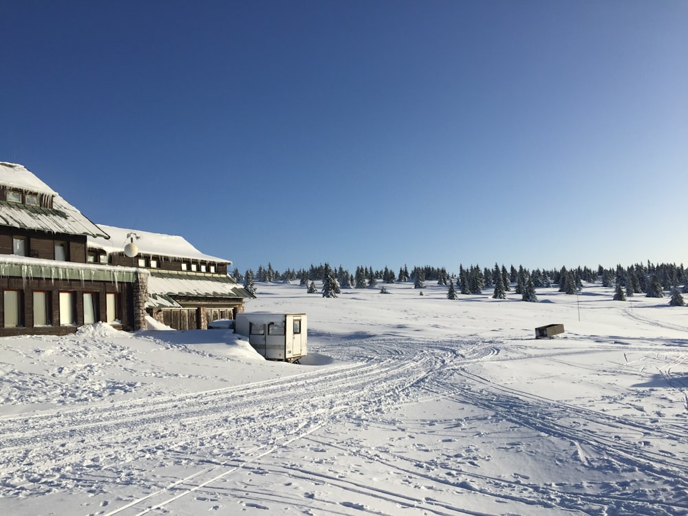 brown wooden house on snow covered ground under blue sky during daytime