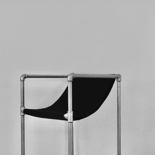 Black and silver chair beside a white wall