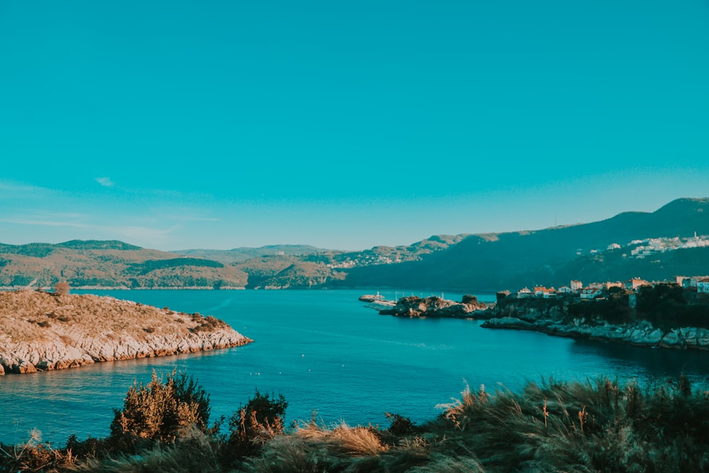 body of water near mountain under blue sky during daytime