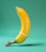 A banana is positioned upright on a textured green background. It is wrapped with a condom over its tip and a rubber band around its midsection.