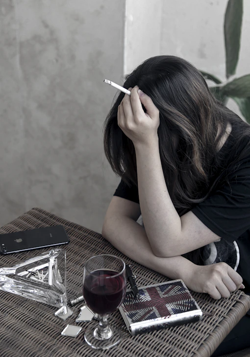 Woman with cigarette and wine glass at table
