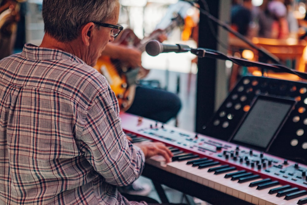 man in white and brown plaid dress shirt playing electric keyboard