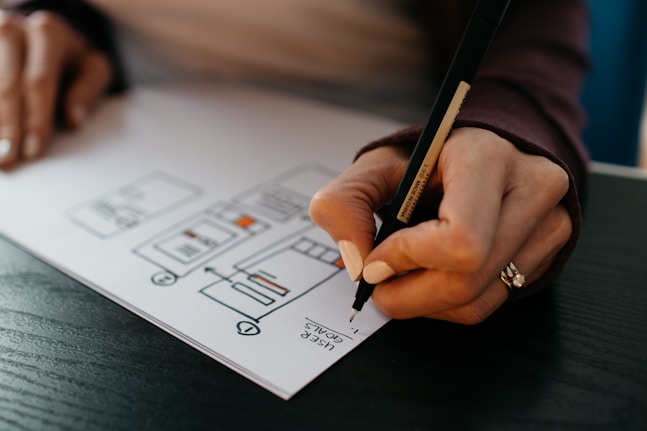 person writing on white paper goal setting 
