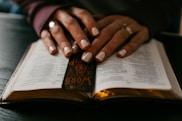 person wearing silver ring on ring finger on book page