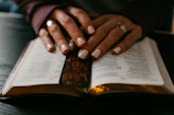 person wearing silver ring on ring finger on book page
