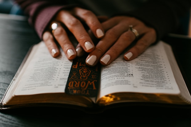 person wearing silver ring on ring finger on book page