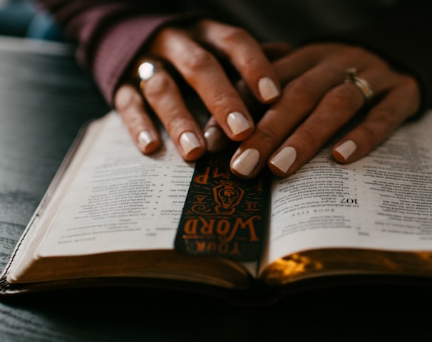 person wearing silver ring on ring finger on book page