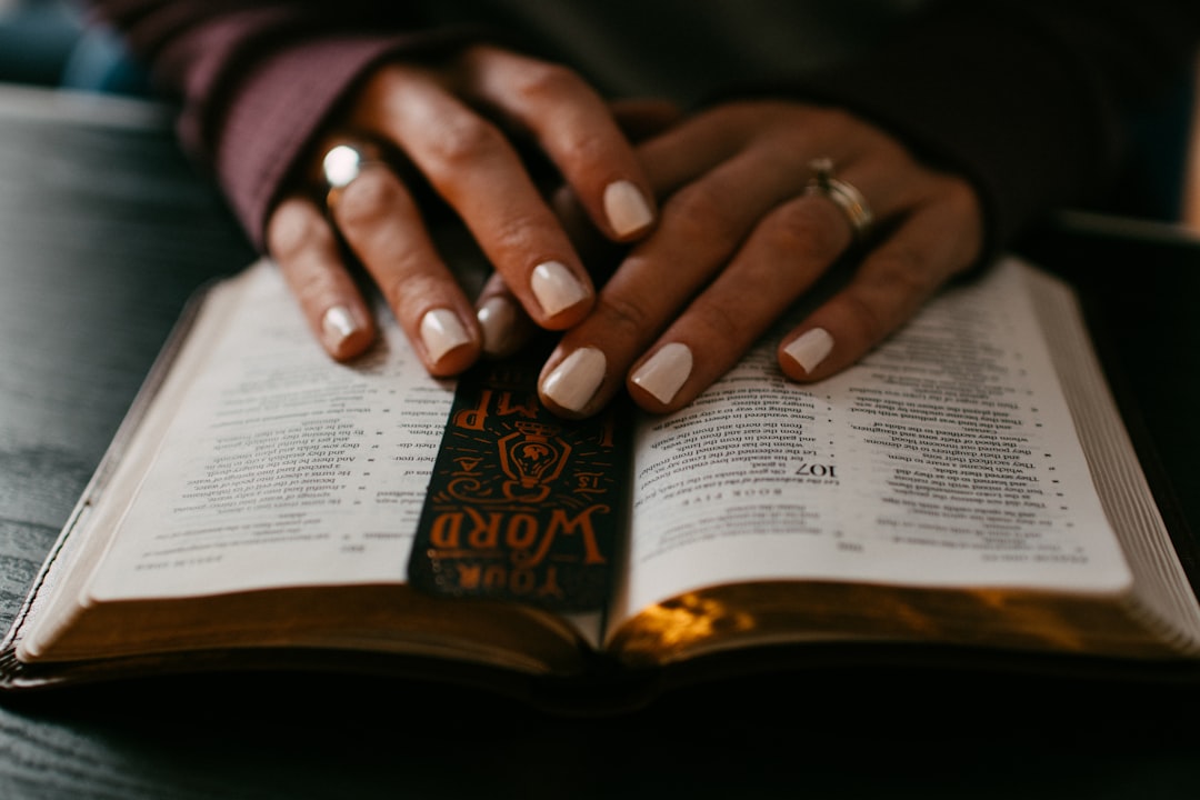 Woman's hands on top of Bible and bookmark open to Psalms