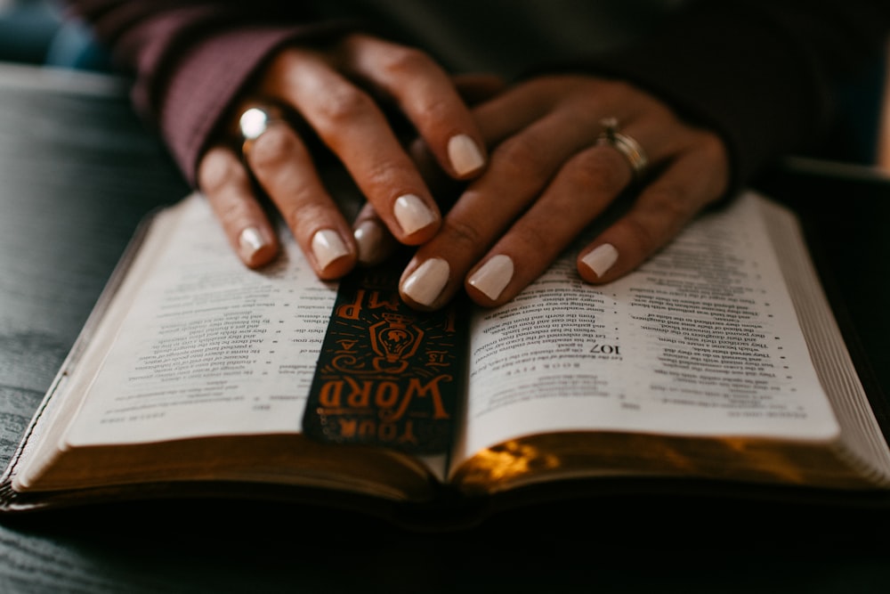 person wearing silver ring on ring finger on book page