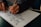 Close-up of hands sketching a website layout on paper with digital devices nearby.