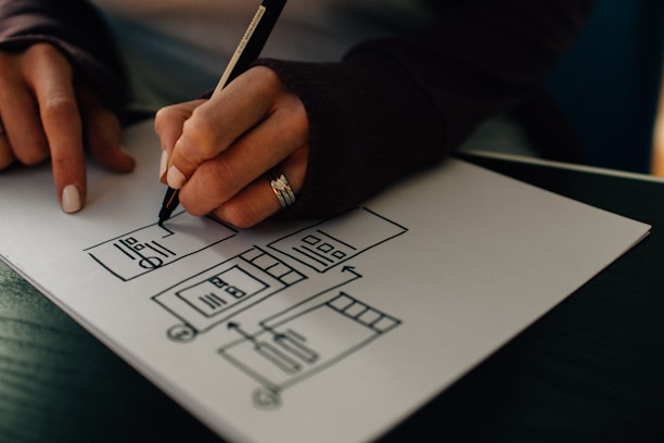 A close-up of a designer sketching website layouts on a notepad.