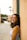 smiling woman in white tank top standing near brown wall during daytime