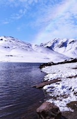 snow covered mountain near body of water during daytime