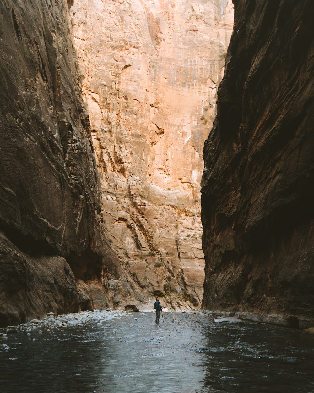 2 people in body of water near brown rock formation during daytime