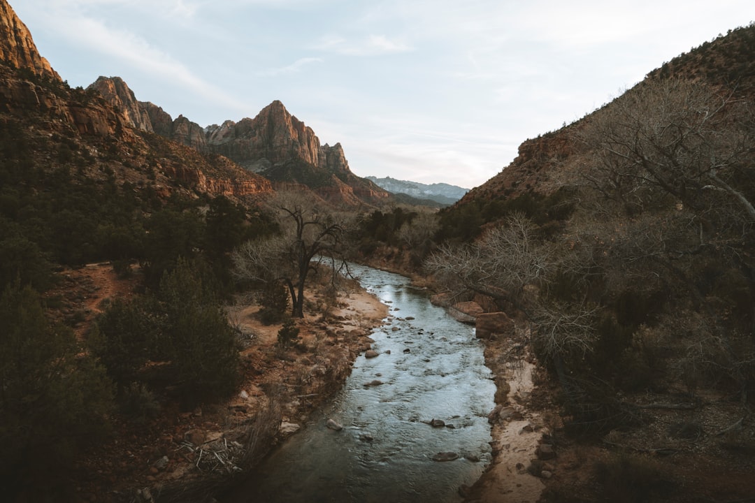 river between mountains under cloudy sky during daytime