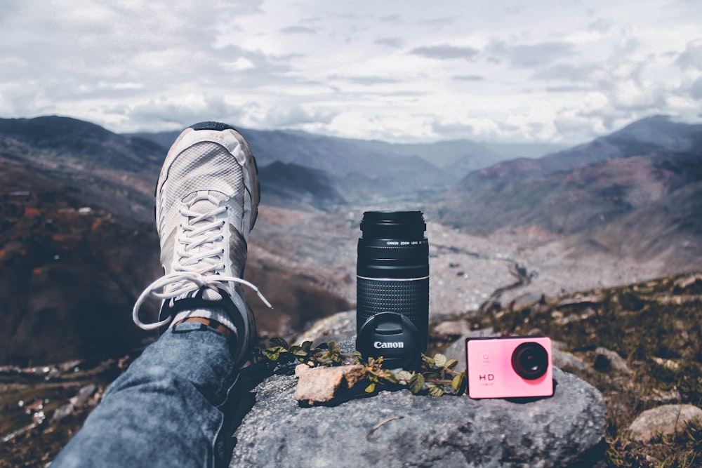 person in blue denim jeans and black and white sneakers sitting on rock during daytime