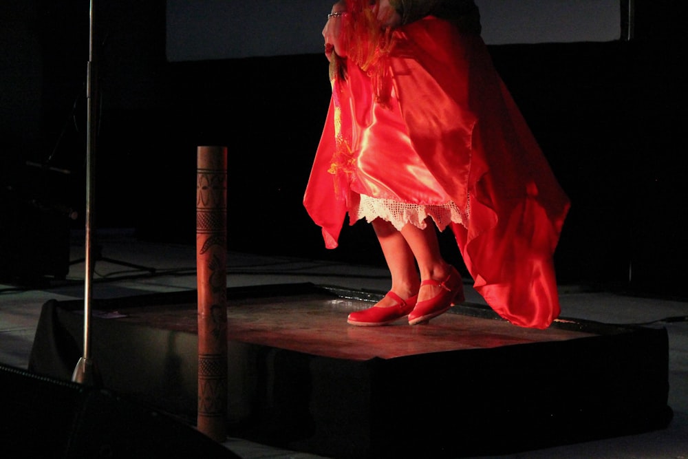 Frau im roten Kleid sitzt auf schwarzem Boden