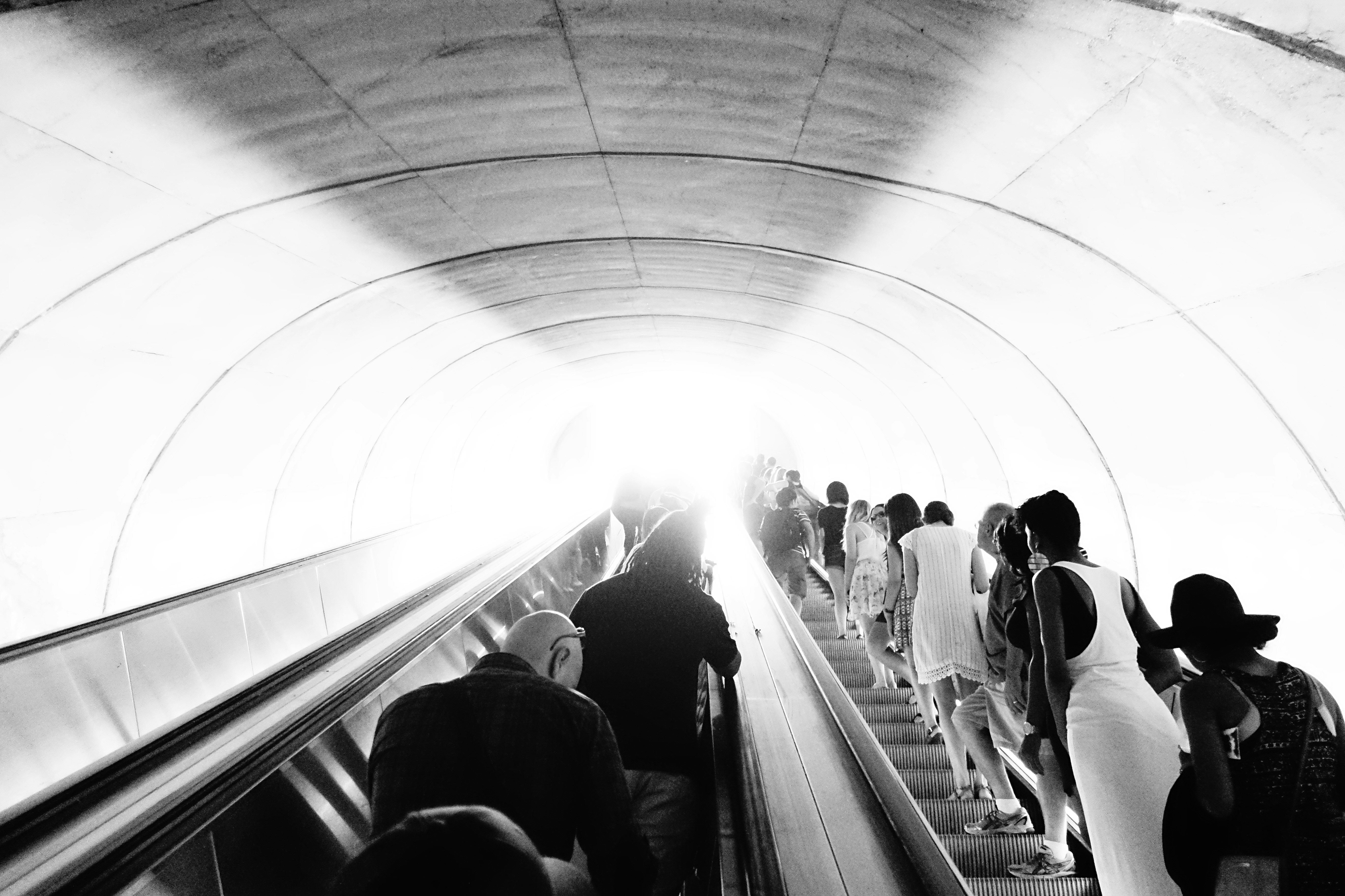 Black and white photo of an escalator leaving the DC metro full of people. 