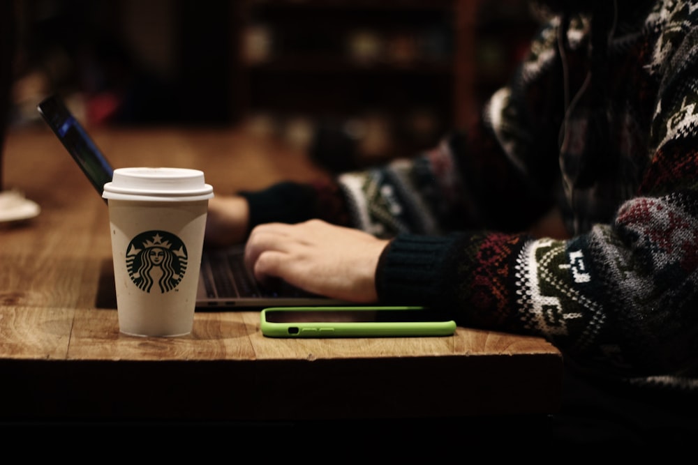 weißer und grüner Starbucks-Becher auf braunem Holztisch