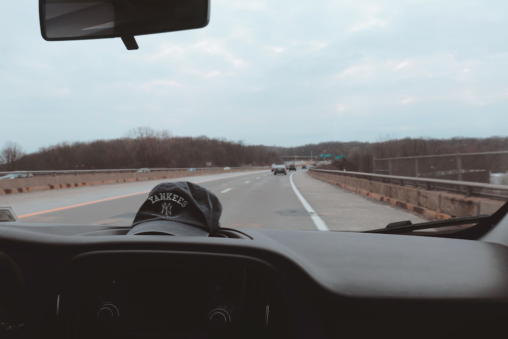 person in black and white cap driving car on road during daytime