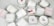 A collection of white candles, some with wooden wicks, arranged haphazardly on a flat surface. The candles are branded with 'French Candle Co' and have variations in size and shape. Some candles have lids with printed designs.