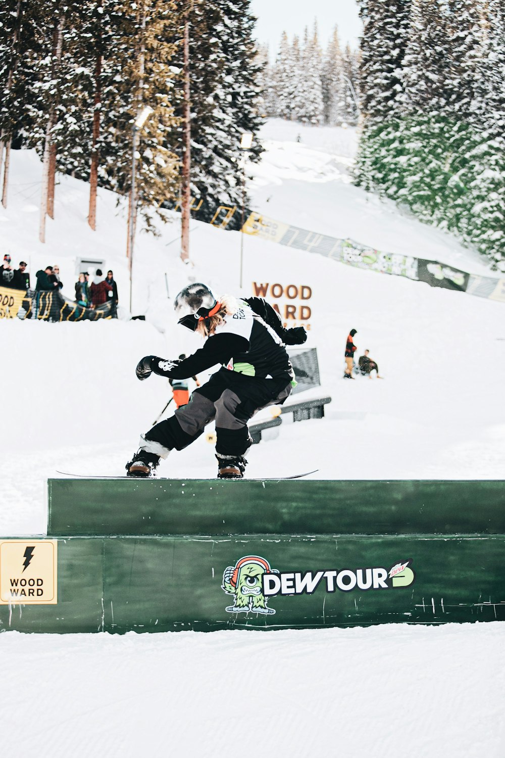 man in black and white ice hockey jersey shirt and black pants riding on black snowboard