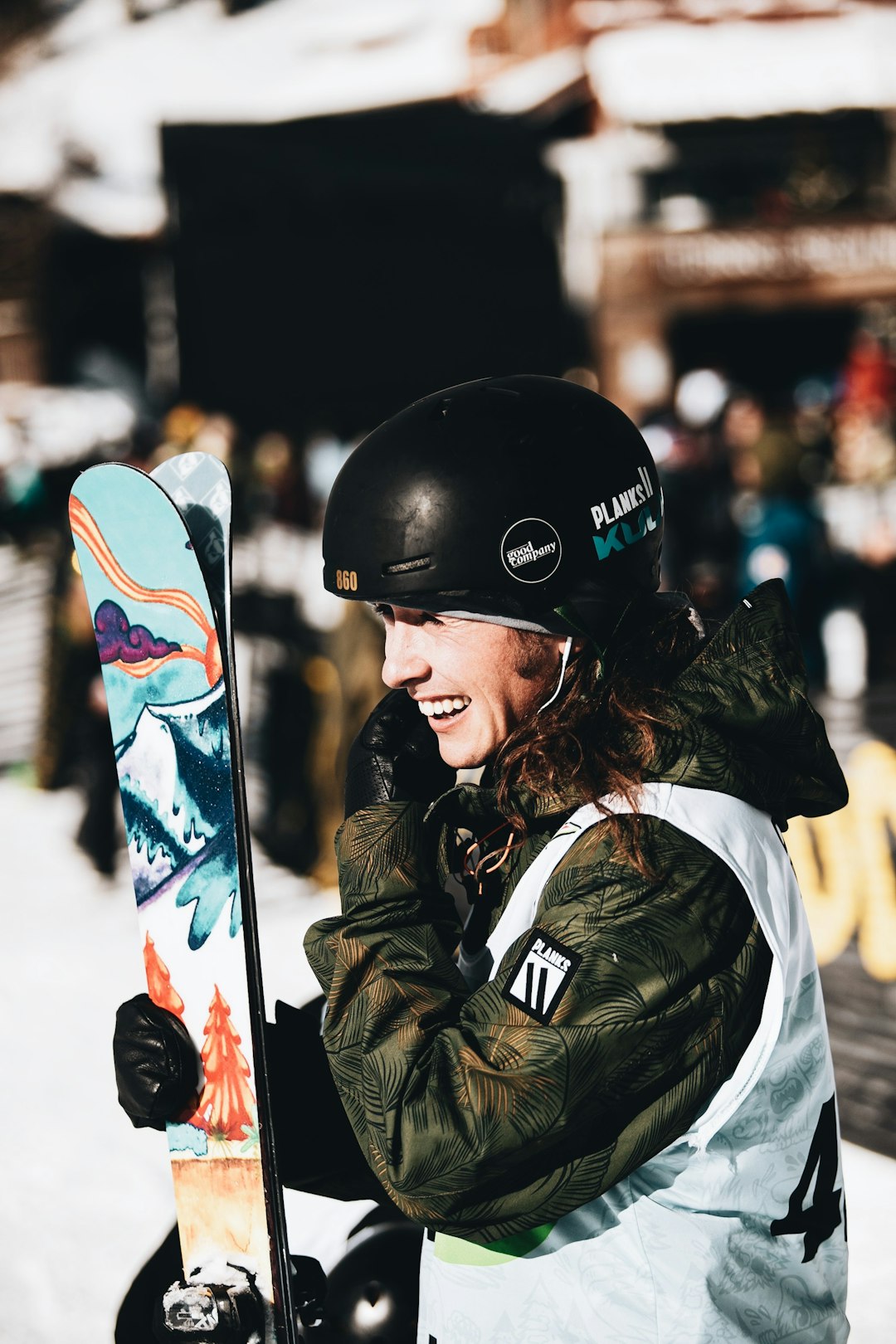 woman in black jacket holding blue and white snowboard