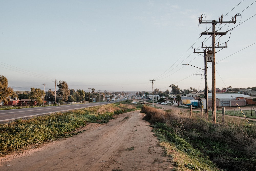 brown dirt road near body of water during daytime