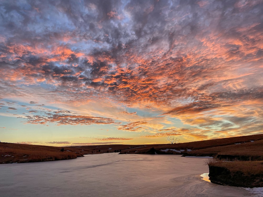 body of water under cloudy sky during sunset