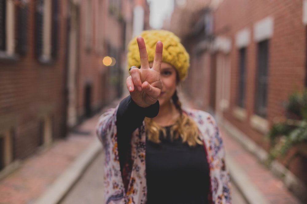 woman in black shirt and brown and white cardigan holding yellow knit cap