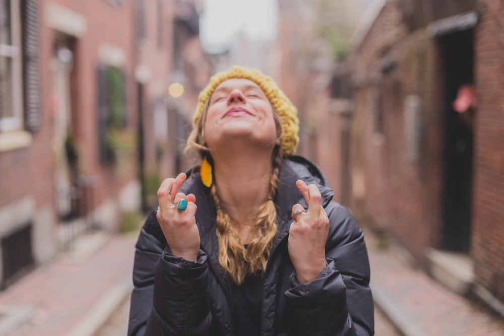 woman in black jacket wearing yellow knit cap