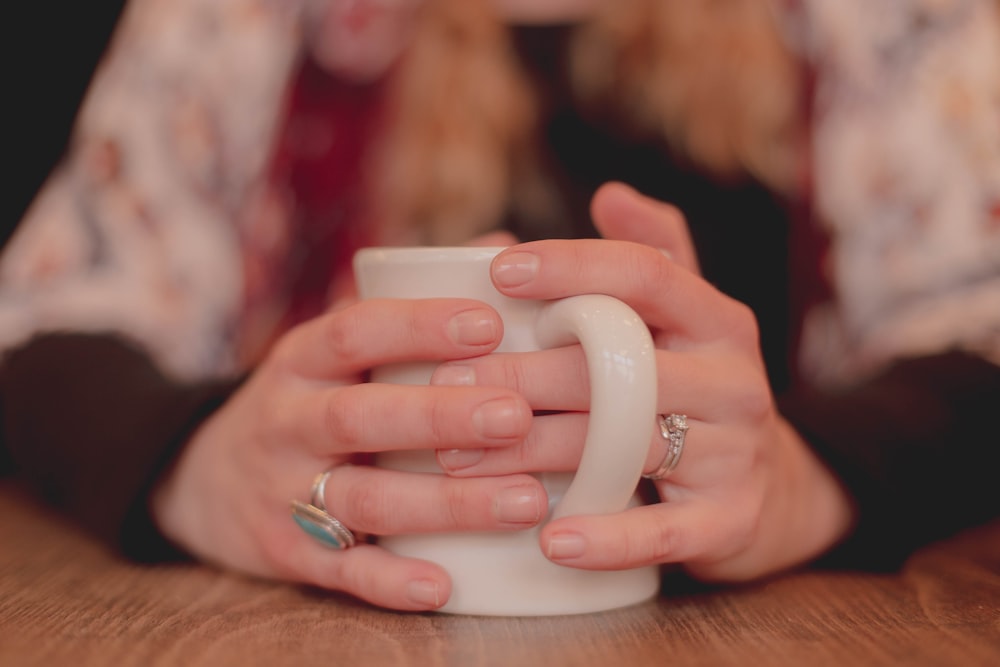 persona sosteniendo una taza de cerámica blanca