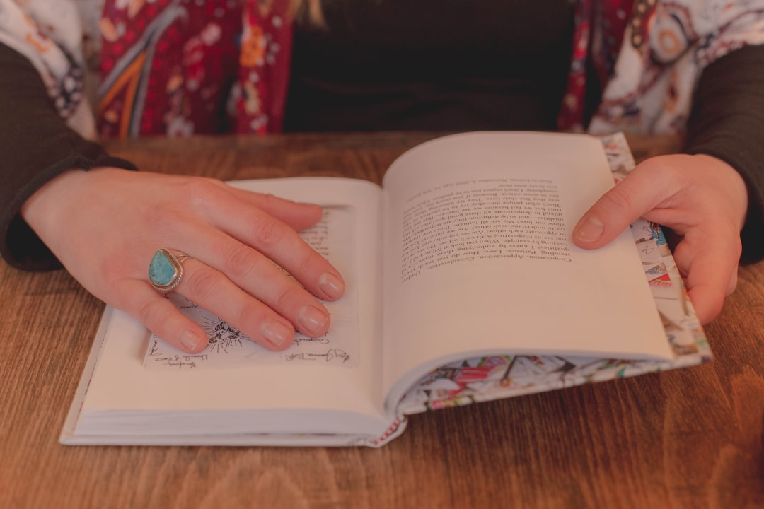 person wearing silver ring holding book