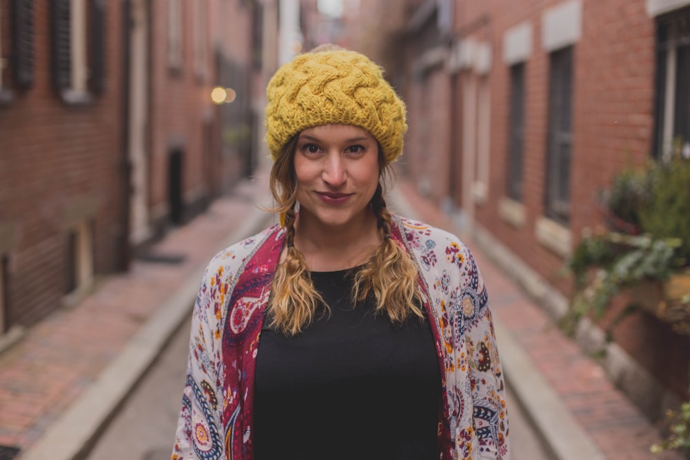 woman in black shirt and white red and blue floral scarf standing on sidewalk during daytime