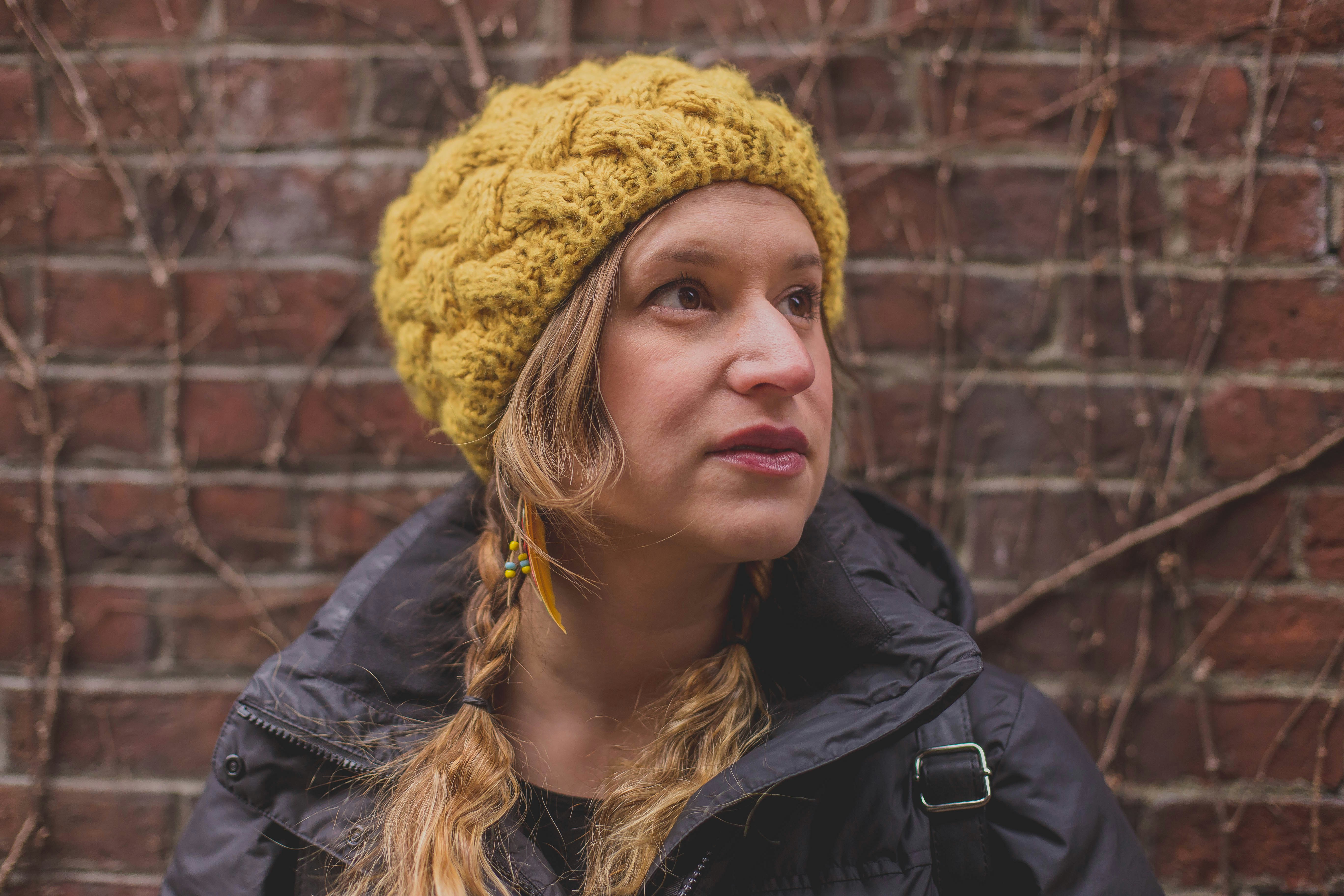 woman in black jacket wearing yellow knit cap