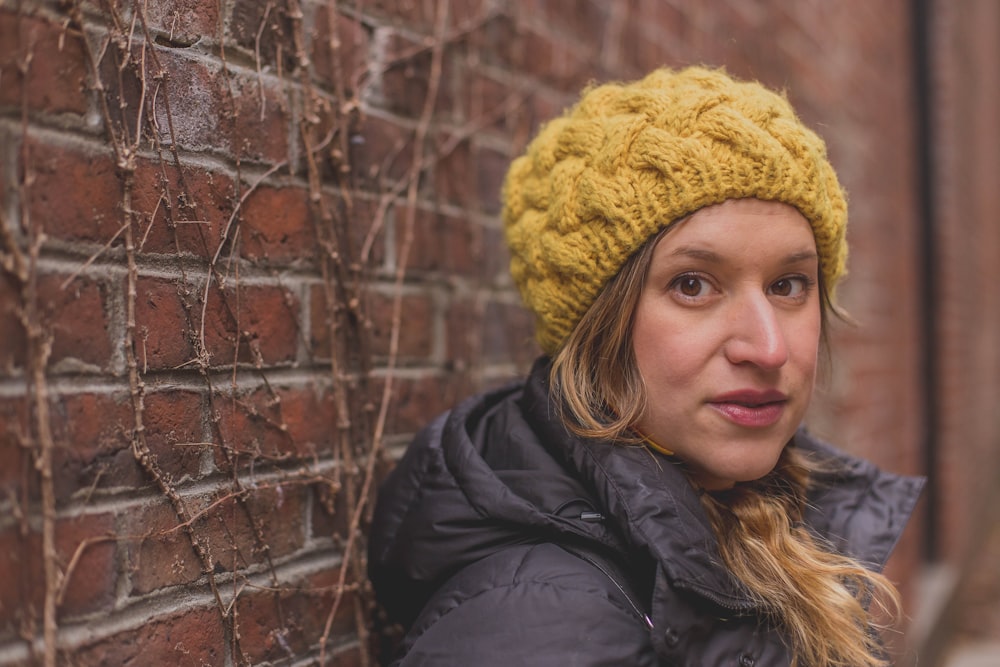 woman in black jacket wearing yellow knit cap