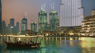 people riding boat on water near city buildings during night time