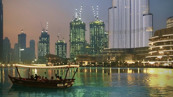 people riding boat on water near city buildings during night time