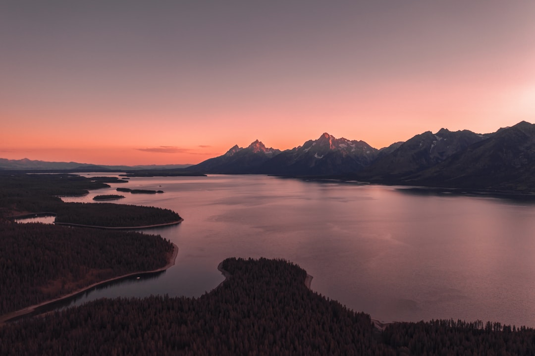 body of water near mountain during sunset