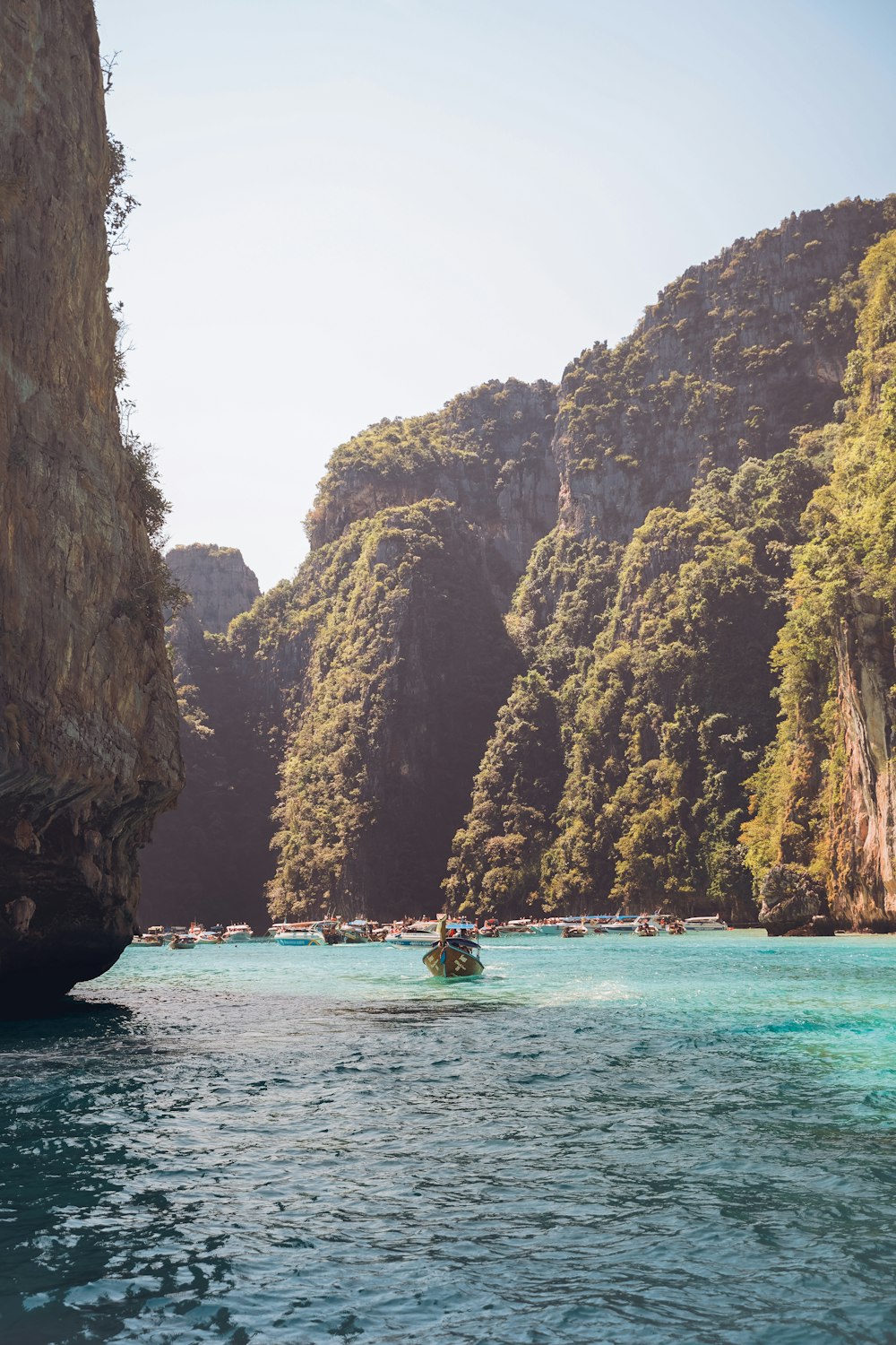 people riding boat on sea near brown rocky mountain during daytime