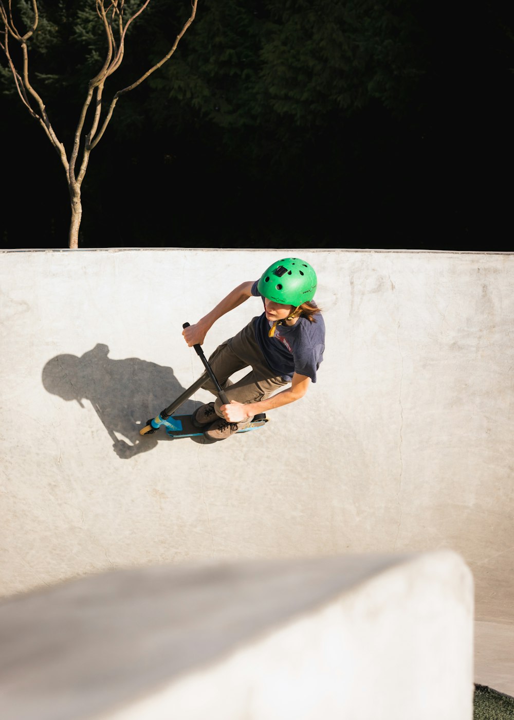 녹색 헬멧을 쓴 소년이 검은 스케이트보드를 타고 있다
