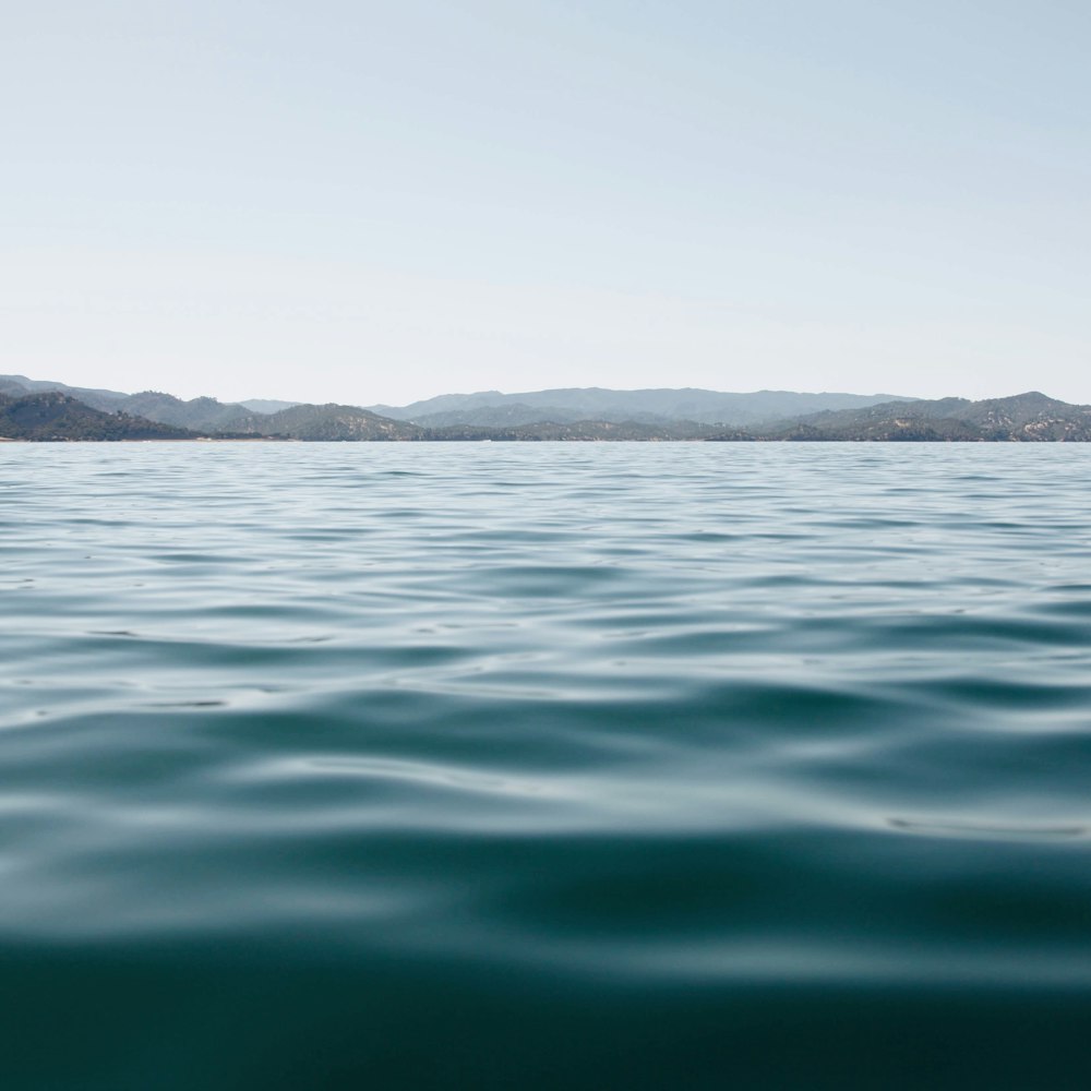 body of water near mountain during daytime