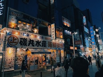 A vibrant street scene in Sapporo's Susukino district at night, showcasing illuminated signs and bustling nightlife.