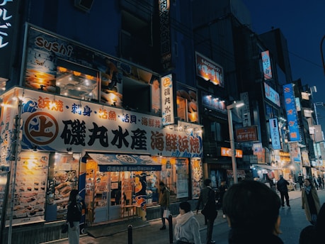 A vibrant street scene in Sapporo's Susukino district at night, showcasing illuminated signs and bustling nightlife.